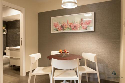 a dining room with a table and white chairs at Living4Malaga Centro Hist&oacute;rico y Playa in M&aacute;laga
