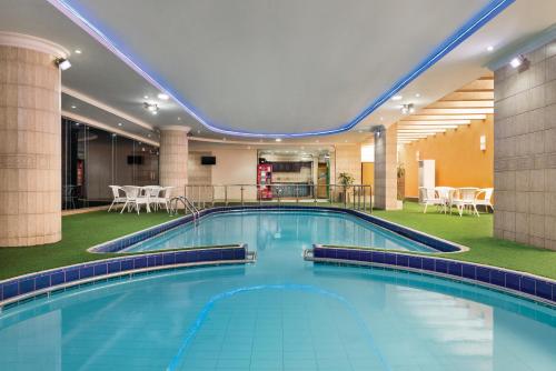 a large pool in a hotel with tables and chairs at Howard Johnson Dammam Hotel in Dammam