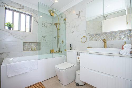a bathroom with a tub and a toilet and a sink at Luxury Retreat Home - 4bed House w/Parking - Mins from CBD in Sydney