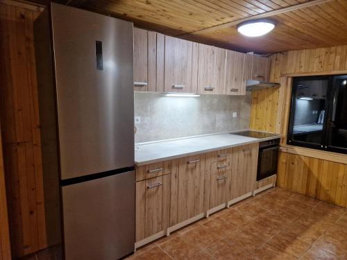 a kitchen with a stainless steel refrigerator and wooden cabinets at Chata Tokarka - Richňavské jazerá in Štiavnické Bane