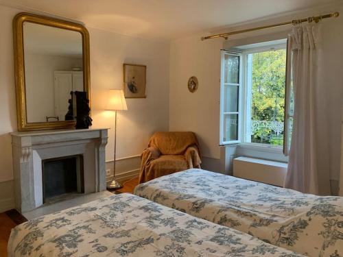 1 Schlafzimmer mit 2 Betten, einem Spiegel und einem Kamin in der Unterkunft Le Clos- Le Pavillon in Lombard