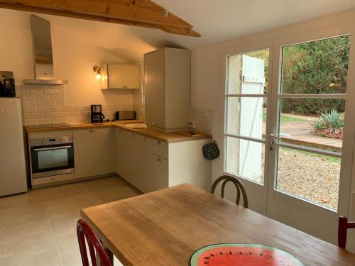 eine Küche mit einem Holztisch und einem großen Fenster in der Unterkunft Le Clos- Le Pavillon in Lombard