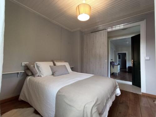 a bedroom with a large white bed and a hallway at A Viña de Lina. Turismo rural con piscina y finca. in Pontevedra