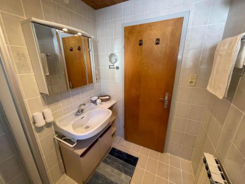 een badkamer met een wastafel en een houten deur bij Sepp, Haus in Finkenberg