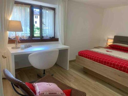 1 dormitorio con cama, escritorio y ventana en Pinzolo, grazioso appartamento, wellness a 100 metri, en Pinzolo