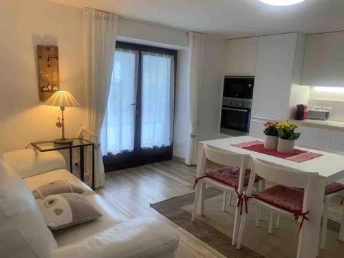 sala de estar con mesa blanca y cocina en Pinzolo, grazioso appartamento, wellness a 100 metri, en Pinzolo