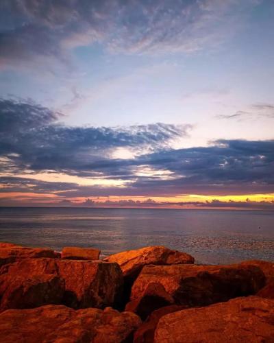 a sunset over the ocean with rocks in the foreground at Next Wave Aparthotel in Batumi