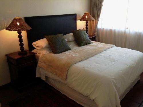 a bedroom with a large bed with two lamps at Bakoven Cottage in Cape Town