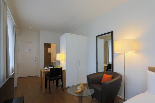 a room with a bed and a chair and a table at Guggach Apartôtel in Zürich