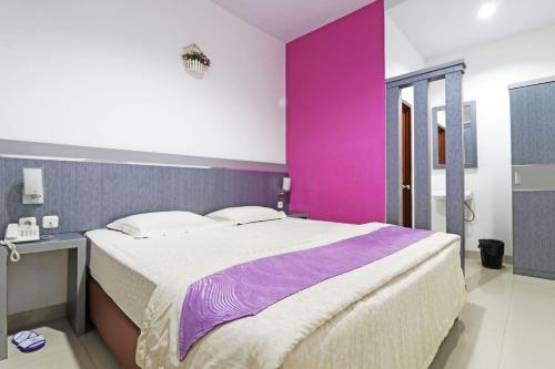 プカンバルにあるPaus Guest House Pekanbaruのピンクの壁のベッドルーム1室(大型ベッド1台付)