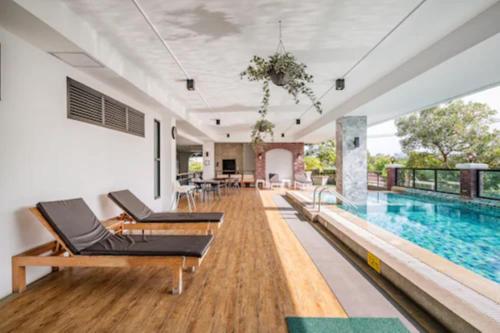 an indoor swimming pool with chairs and a swimming pool at The Corner Lodge in Pattaya