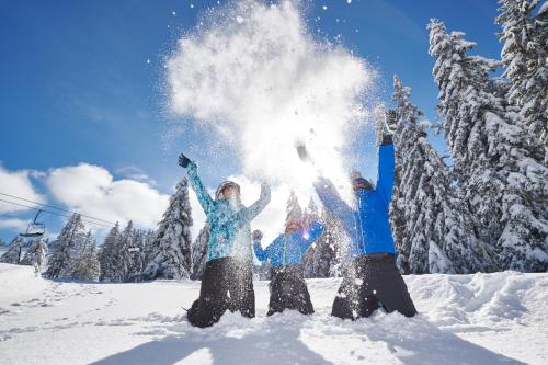 three people standing in the snow with their arms up at Terme Zreče – Hotel Atrij in Zreče