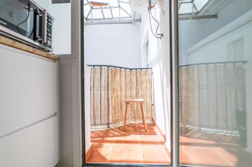 Blick auf einen Balkon mit einem Hocker durch ein Fenster in der Unterkunft Maria´s Home in Málaga