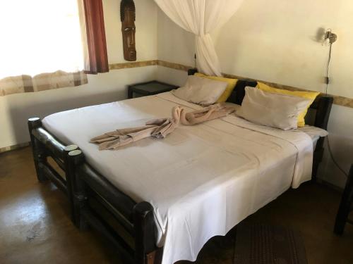 a bed with white sheets and towels on it at Thokozani Lodge in White River