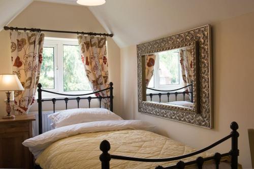 a bedroom with a bed and a mirror at Meddlars a historic cottage on the countryside edge of a vibrant Market Town in Hadleigh