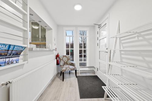 a white hallway with a chair and a window at Acco Guesthouse in Akureyri