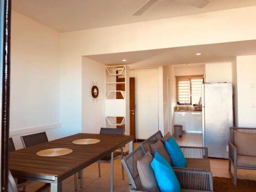 uma sala de jantar com uma mesa de madeira e almofadas azuis em Lovely 3-bedroom at Azuri Ocean & Golf village em Roches Noires