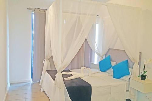 a bedroom with a white bed with blue pillows at Lovely 3-bedroom at Azuri Ocean & Golf village in Roches Noires