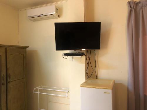 a flat screen tv on a wall next to a refrigerator at Hotel Bar Restaurant Emergency 911 STO LK GROUP in Paramaribo