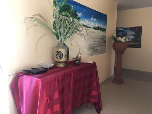 a table with a vase with a plant on it at Hotel Bar Restaurant Emergency 911 STO LK GROUP in Paramaribo
