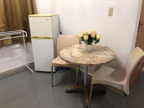 a table with a vase of flowers and a refrigerator at Hotel Bar Restaurant Emergency 911 STO LK GROUP in Paramaribo