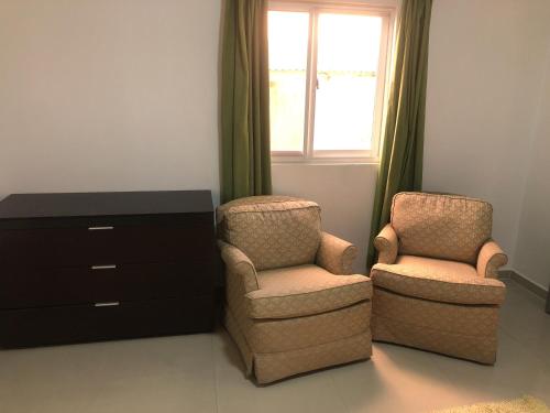two chairs and a dresser in a room with a window at Hotel Bar Restaurant Emergency 911 STO LK GROUP in Paramaribo