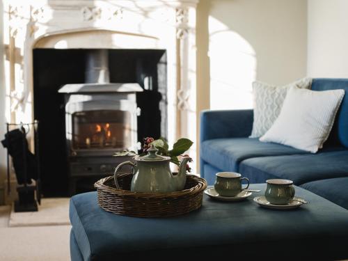 een woonkamer met een theepot en twee kopjes op een tafel bij Rose Cottage, Rodborough in Stroud