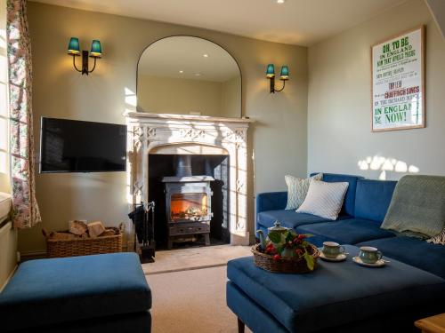 a living room with a blue couch and a fireplace at Rose Cottage, Rodborough in Stroud