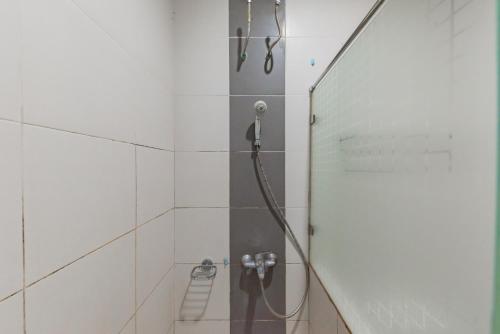 a shower with a hose in a white tiled bathroom at KoolKost @ The Casa 18 (minimum stay 30 nights) in Bandung