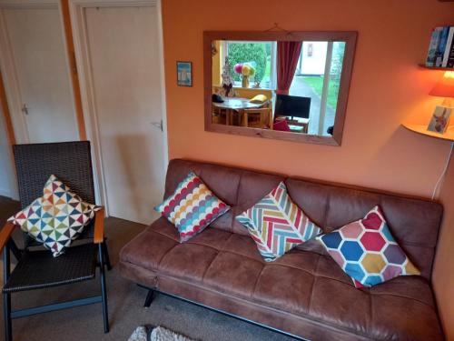 sala de estar con sofá de cuero marrón con almohadas en Bray Cottage, en Sidmouth
