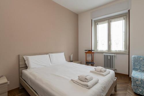 Un dormitorio con una cama blanca con toallas. en I Host Apartment - Giambellino 40, en Milán