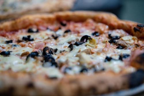 a pizza with black olives and cheese on a table at Mandachi Hotel & SPA in Suceava