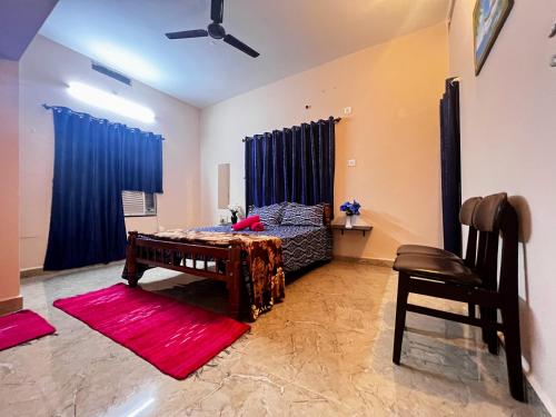 a bedroom with a bed with blue curtains and a red rug at Peaceful villa amidst greenery within the city. in Manipala