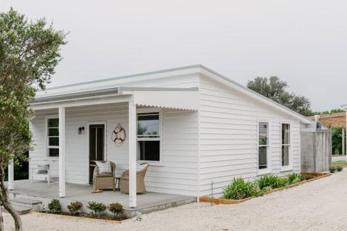 a white tiny house with a porch at Port Cottage on the Great Ocean Road in Port Campbell