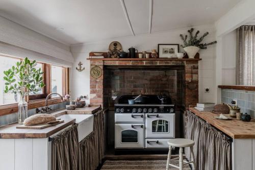 a kitchen with a stove and a brick fireplace at Port Cottage on the Great Ocean Road in Port Campbell