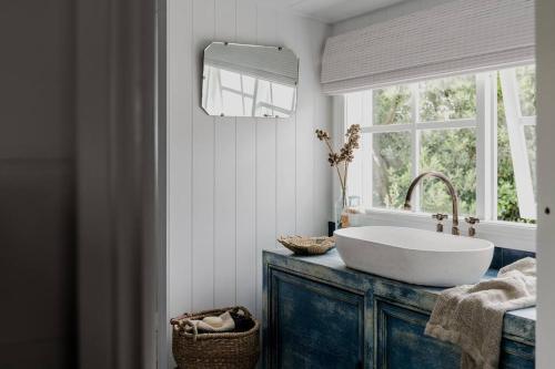 baño con lavabo blanco y ventana en Port Cottage on the Great Ocean Road, en Port Campbell