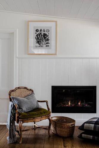 a living room with a chair and a fireplace at Port Cottage on the Great Ocean Road in Port Campbell