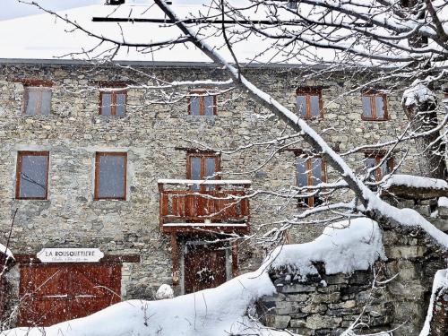un viejo edificio de piedra en la nieve con un árbol en La Bousquetière, en Jausiers