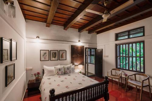 a bedroom with a bed and chairs in a room at SaffronStays Amaya, Kannur - 300 years old heritage estate for families and large groups in Kannur