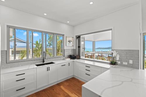 a white kitchen with white cabinets and windows at Club Wyndham Airlie Beach in Airlie Beach