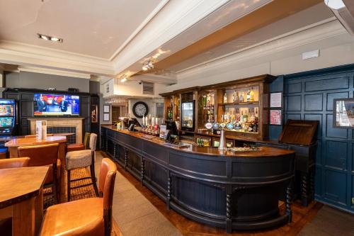a bar in a restaurant with tables and chairs at The Railway by Innkeeper's Collection in Hornchurch