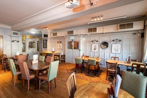 a dining room with wooden tables and chairs at The Railway by Innkeeper's Collection in Hornchurch