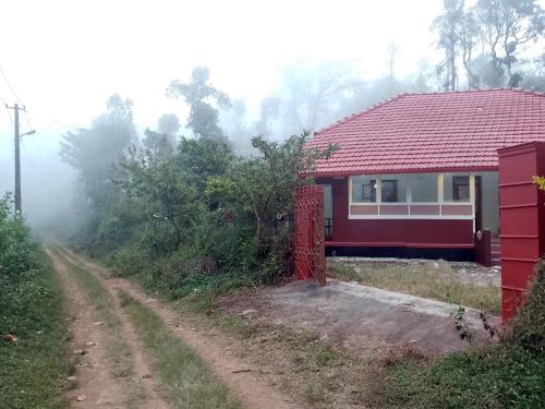 ein rotes Haus mit rotem Dach auf einer unbefestigten Straße in der Unterkunft Chilly Coorg in Virajpet