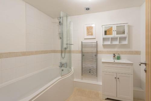 a white bathroom with a tub and a sink at Pondside Barn in Long Wittenham