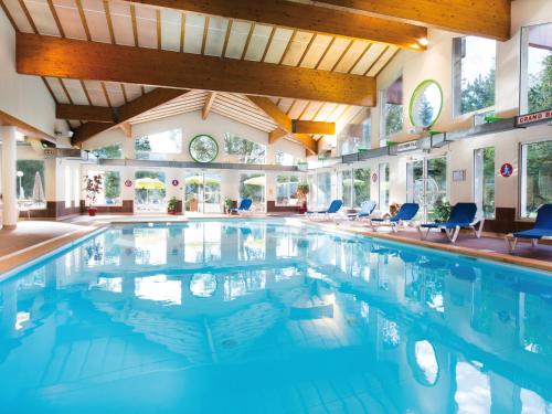 - une piscine avec des chaises bleues dans un bâtiment dans l'établissement Club Vacances Bleues Les Alpes d'Azur, à La Salle Les Alpes