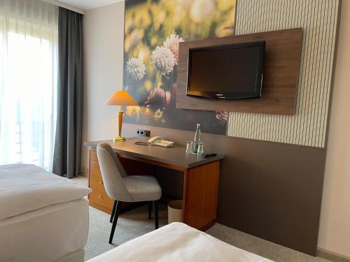 a hotel room with a desk and a tv on a wall at Mercure Hotel Gera City in Gera