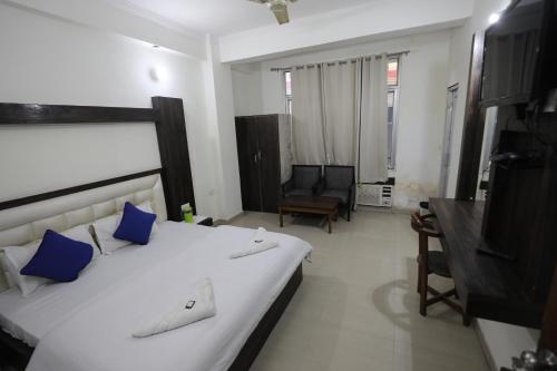 una camera da letto con un grande letto bianco con cuscini blu di Hotel Neelkanth Katra Managed By Mahadev Hotel and Resorts a Katra