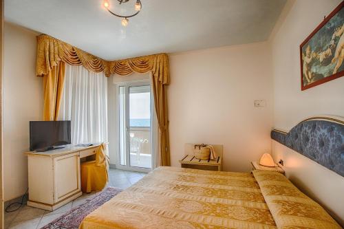 - une chambre avec un lit, une télévision et une fenêtre dans l'établissement Hotel Elpiro, à Lido di Jesolo