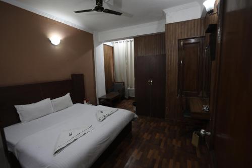 a bedroom with a bed with white sheets and a ceiling at Mahadev Hotel and Resorts in Katra