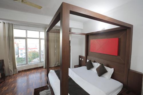 a bedroom with a canopy bed with a large window at Mahadev Hotel and Resorts in Katra